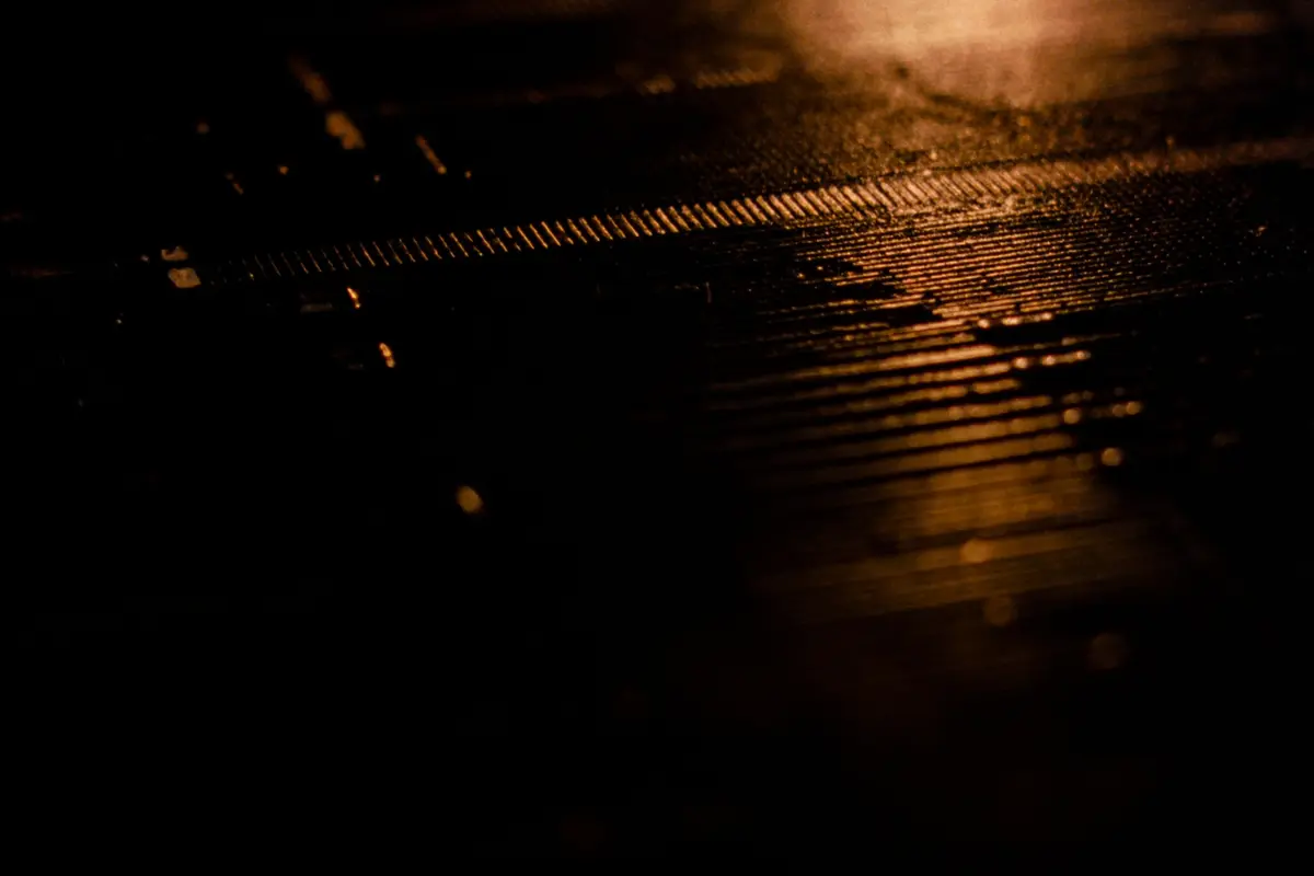 Amber light raking across dark machined metal